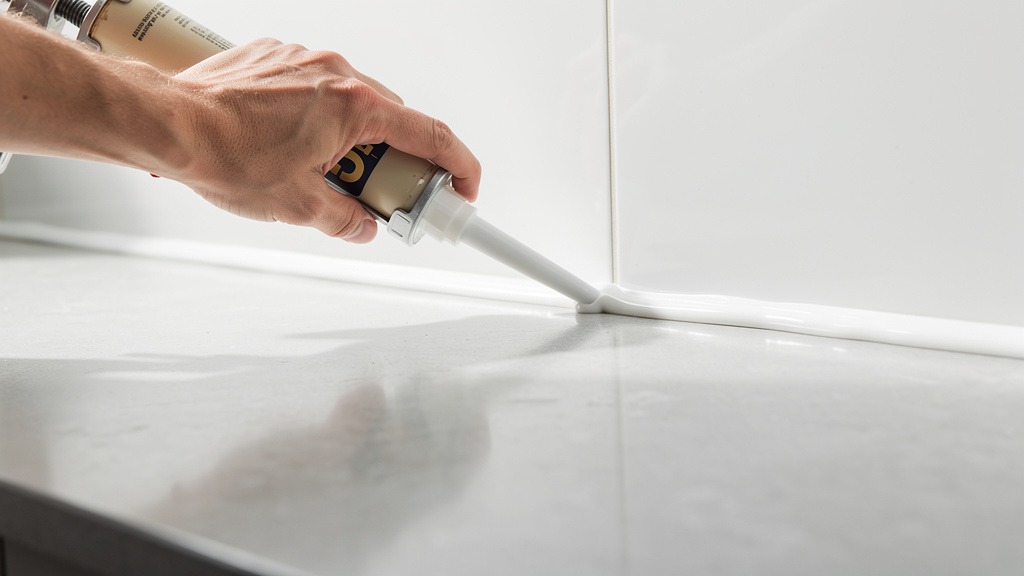 Application de mastic silicone sur le joint plan de travail et mur